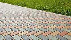 picture of a red, brown, and gray paver driveway in geometric pattern. we will do the required brick mortar repairs for you